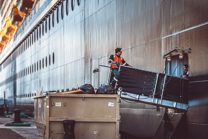 a man standing on top of a truck next to a large ship